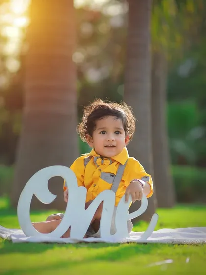 Celebrating one year with a bright and sunny outdoor photoshoot. We use props like this "One" sign to mark the special occasion while capturing your baby's happy personality.