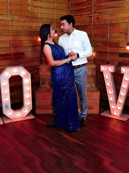 A candid moment from the 'LOVE' marquee light pre-wedding shoot, capturing a genuine interaction between the couple.