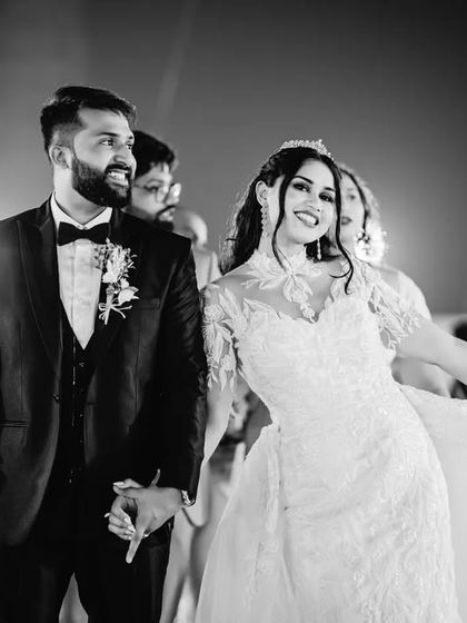 A candid black and white photo of the bride twirling as she and the groom walk hand-in-hand. It's a moment of pure, unscripted joy.