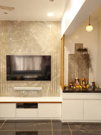 A modern living room design featuring a TV unit with a marble-finish wall, integrated temple space, and clean white cabinetry.
