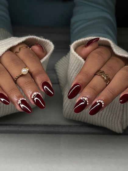 The full two-hand view of the red and pearl manicure. The pearl accent adds a touch of timeless elegance to the bold red color.