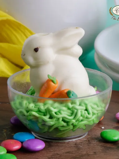 Our 'Bunny in a Globe' is a cute Easter treat featuring a white chocolate bunny nestled in a bed of green frosting 'grass'.