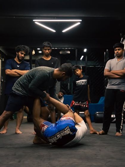 A coach demonstrates a submission from the guard position as students watch and learn.