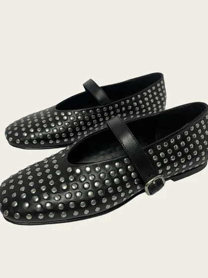 A clean product shot of the black studded ballet flats with a single strap and buckle. This angle highlights the craftsmanship and the dense pattern of the hand-applied studs that cover the shoe.