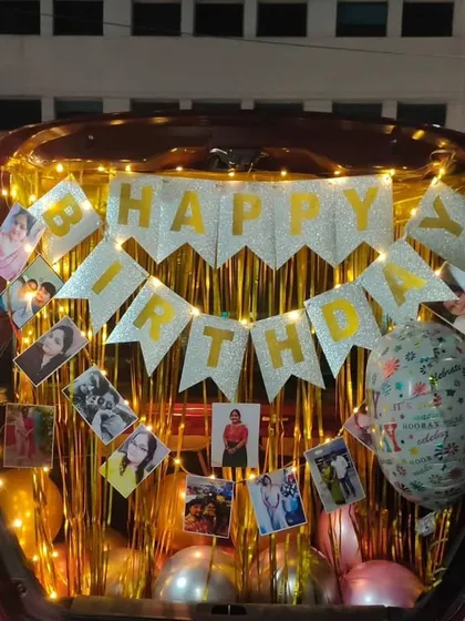 A surprise that's personal and full of memories. This car trunk decoration for a birthday includes a shimmering backdrop, fairy lights, and a banner of personal photos, showing how I can tailor any surprise to your story.