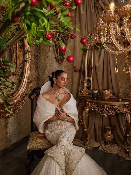 An ivory fit-and-flare gown that celebrates contrast. The corseted bodice sculpts the form, while a dramatic hooded panel adds quiet power, creating an unforgettable look.