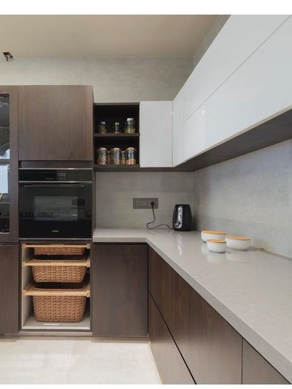 Detail of the dual-tone kitchen, showing the seamless integration of appliances and storage solutions. Wicker baskets for vegetables and a dedicated spice rack are examples of how I prioritize practical, clutter-free kitchen design.