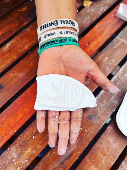 A hand holding a carved piece with the iconic Royal Enfield logo, a perfect memento from the Rider Mania festival.