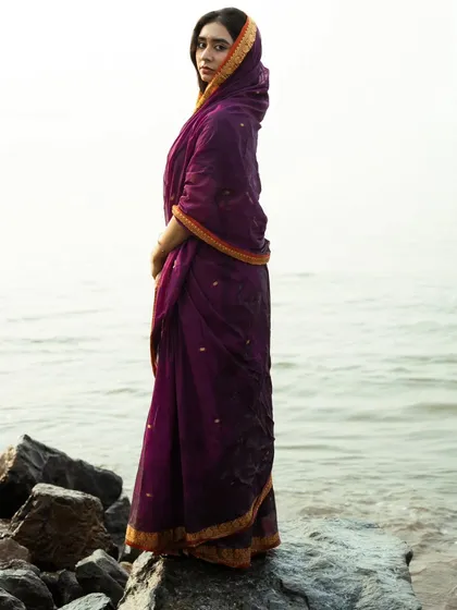 A profile shot that highlights the traditional way the saree is draped, with the endless sea as a simple, beautiful background.