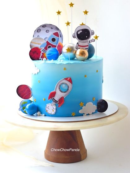 A different view of the space theme cake, showing the hanging star toppers and planetary decorations.