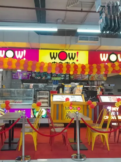 A full view of the WOW! Momo store opening decoration, showing how balloon garlands across the storefront and entrance pillars create a cohesive and celebratory look.