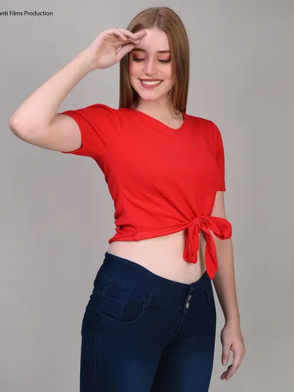 A vibrant shot of a model in a red tie-front crop top. The bright color and cheerful pose are designed to grab attention on crowded e-commerce pages.