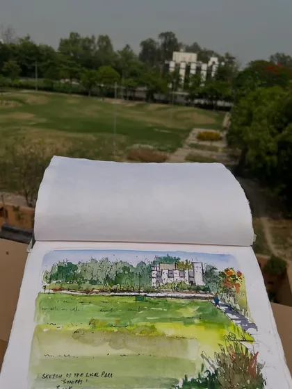 Holding up my sketchbook with the park view. Even in a new place, finding moments to sketch brings a sense of calm and creativity.