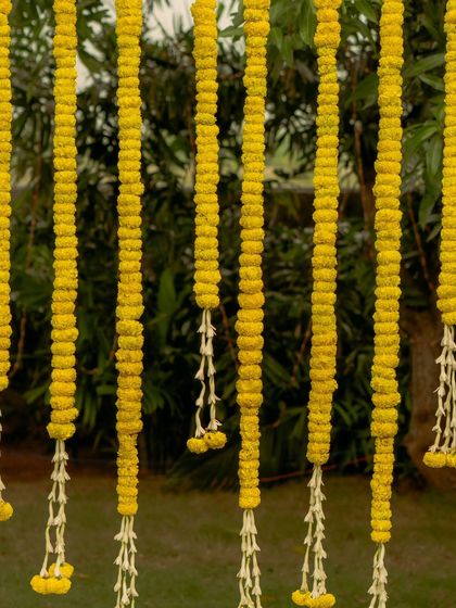 A close-up of the hanging marigold and tuberose garlands. Using local, seasonal flowers is a core part of my sustainable approach to decor, adding natural beauty and fragrance.