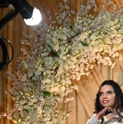 A bride posing near an arch of delicate white cherry blossoms. The soft, romantic lighting highlights both her and the intricate floral work.