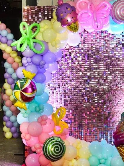 A shimmering photo booth framed by a rainbow of candy-colored balloons and giant sweet decorations, creating the perfect spot for memorable pictures.