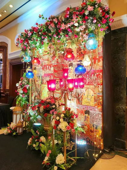 An angled view of the colorful photo corner, highlighting the layers of flowers, lanterns, and textiles. The warm lighting creates an inviting and richly detailed spot for guest photos.
