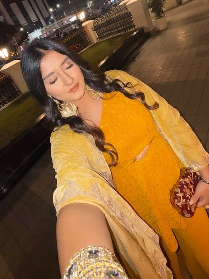 A selfie in a stunning yellow ethnic outfit, perfect for a wedding or festive event. The heavy earrings and wavy hair complete the glamorous look.