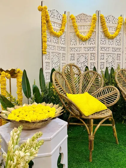 A classic and elegant Diwali setup. We used bright yellow marigolds, traditional brass urlis, and stylish peacock chairs against a carved white screen for a festive feel.