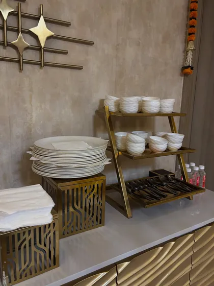 A neat and tidy crockery station for a house party, featuring stacked plates, bowls, and cutlery organized for guest convenience.