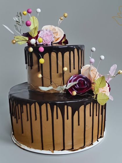A stunning two-tier chocolate drip cake that's perfect for any celebration. Adorned with delicate sugar flowers, this cake combines rich chocolate flavor with elegant floral design.
