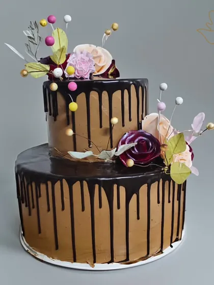 An elegant two-tier chocolate drip cake, adorned with delicate wafer paper flowers. This sophisticated design is perfect for anniversaries, bridal showers, or milestone birthdays.