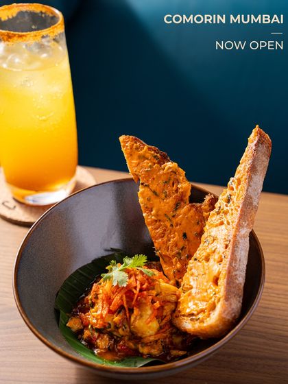 A bowl of our flavour-packed food, served with crispy bread and a bright, citrusy cocktail. This is elevated comfort food, Comorin style.