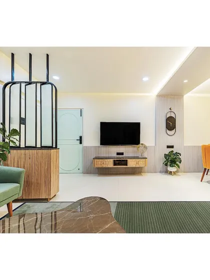 A modern living room with a mix of bold colors and textures. The green sofa, mustard yellow couch, and fluted partition create a dynamic and visually interesting space.