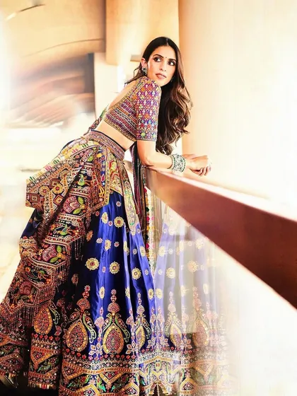This vibrant, multi-colored lehenga is for the bride who loves color. The intricate threadwork and deep blue skirt create a look that is joyful, traditional, and absolutely stunning.