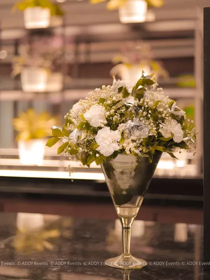 A sophisticated floral arrangement in a silver goblet-style vase. This classic decor piece adds a touch of elegance to registration desks, bars, or VIP lounges at a formal corporate event.