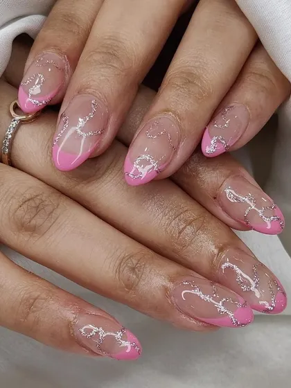 A modern design with pink French tips and abstract silver glitter lines over a sheer nude base.