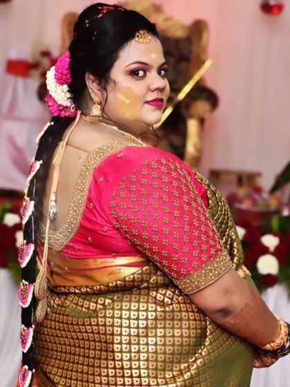A beautiful shot from the back, highlighting the detailed work on the blouse and the traditional poola jada hairstyle. The combination of the embroidered blouse and floral hair accessories creates a stunning traditional look.