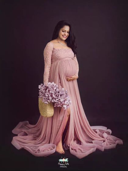 The definition of elegance. This mom-to-be looks radiant in our pink lace gown, with the long train spread out beautifully around her.