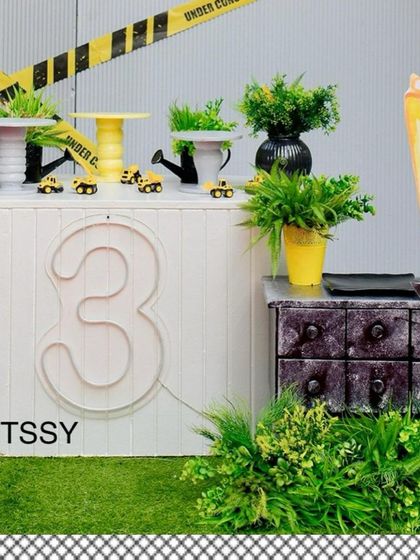 A modern and clean construction-themed party for a 3rd birthday. This setup features a neon number "3," "under construction" tape, and excavator props for a fun and stylized party zone.
