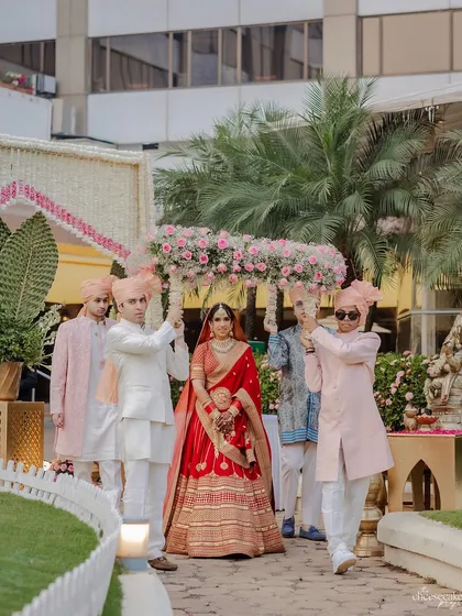 The bride's entrance under a phoolon ki chaadar designed to match the mandap decor, featuring a dense arrangement of pink flowers.