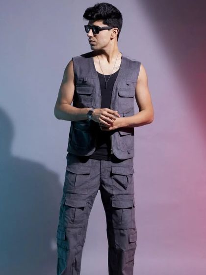 A studio shot of a men's utility vest and cargo pants set. The dual-tone lighting adds dimension and a modern feel to this functional, military-inspired streetwear look.