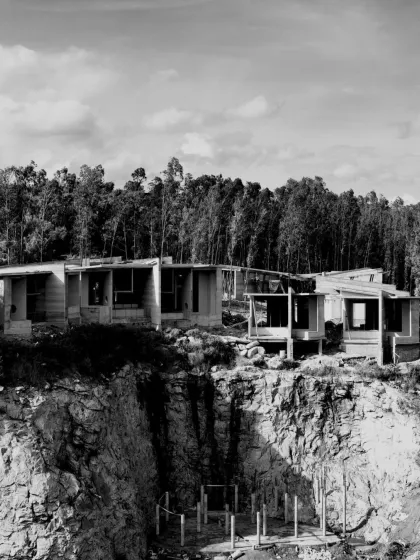 Sculpting spaces that echo the landscape. Multiple cottages are seen under construction, seamlessly blending their forms with the raw beauty of the terrain.