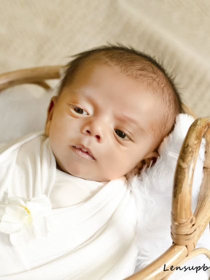 A classic newborn portrait showing a baby resting peacefully in a rustic basket. The soft, neutral tones of the wrap and blanket ensure that your baby remains the gentle focus of the image.