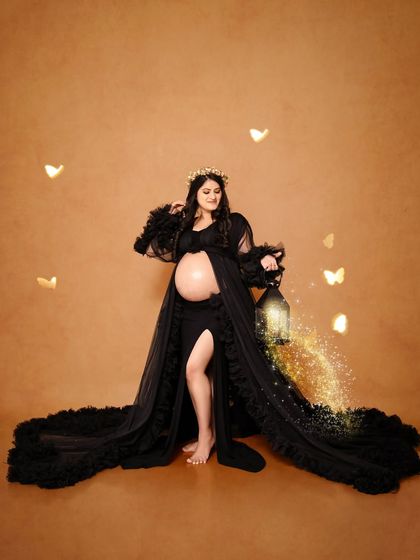 A magical solo portrait in a black ruffled gown. We added a touch of sparkle with a lantern prop and digital butterfly effects to create a whimsical, fairytale-like scene.
