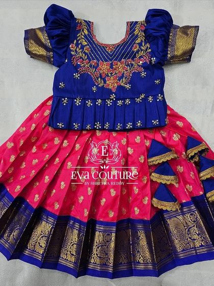 A newborn-sized blue and pink Pattu Pavadai with a pleated peplum blouse and cascading tassels.