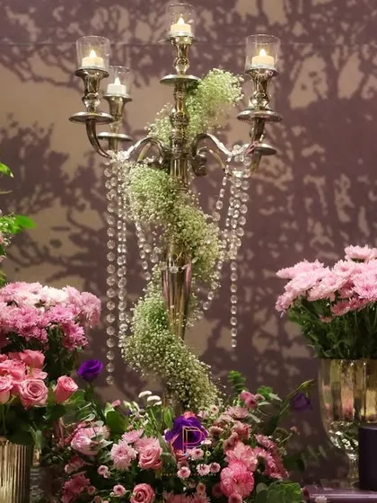 A close-up of the candelabra, showing how the cascading crystals and delicate baby's breath create a soft, ethereal effect against the rich floral arrangements.