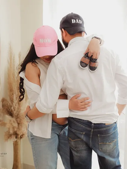 A sweet and modern couple's pose with "Mom" and "Dad" hats. This lifestyle shot is full of love and excitement for their new roles.