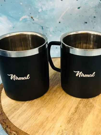 A pair of personalized black stainless steel mugs. These are durable and perfect for keeping drinks hot or cold.