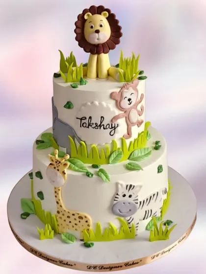 A charming two-tier jungle theme cake for a first birthday. The cake features cute, hand-painted jungle animals like a lion, monkey, giraffe, and zebra.
