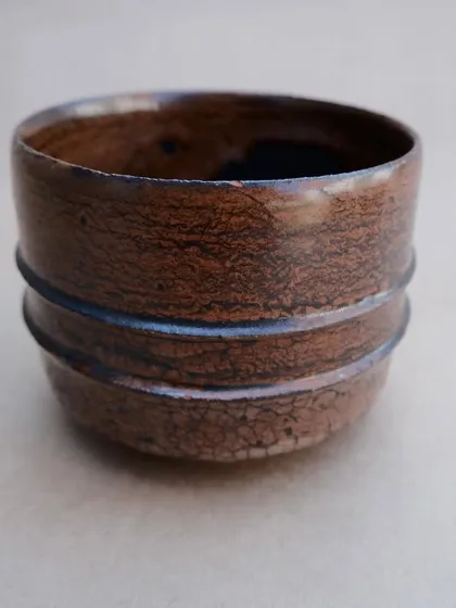 A close-up of a Raku-fired teabowl. The crackle pattern in the glaze, known as 'crazing', is a characteristic feature of this technique.