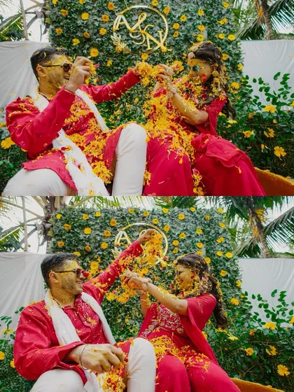 The couple playfully showers each other with flower petals against a beautiful floral wall.