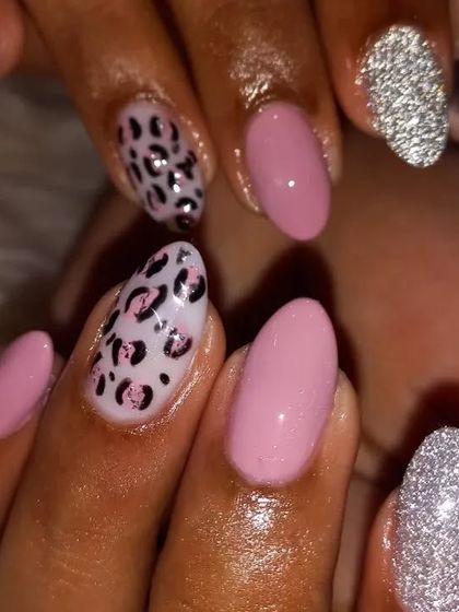 A cute and trendy combination of soft pink, silver glitter, and a delicate leopard print on almond-shaped nails.