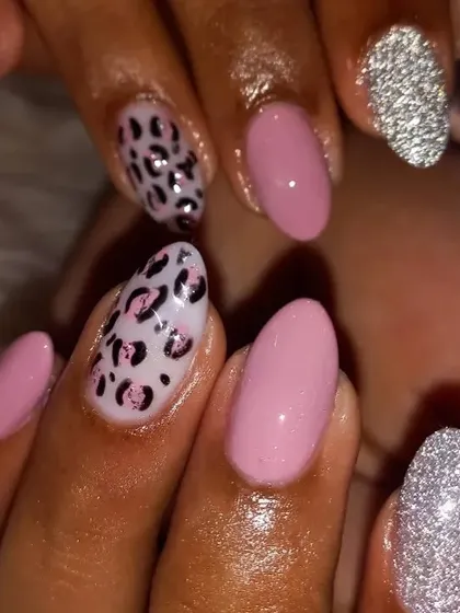 A fun and stylish manicure combining soft pink nails with bold accent nails. The design features a playful pink and black leopard print and a full-coverage silver glitter nail.