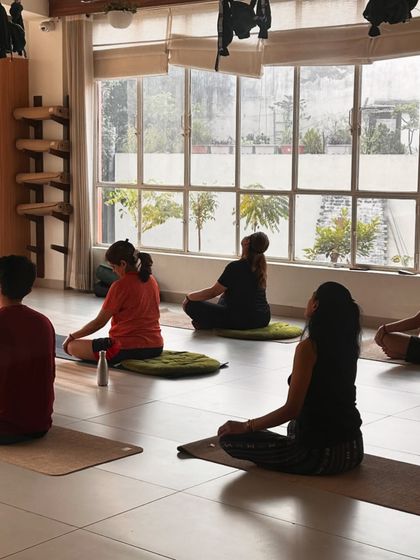 A quiet moment during a daytime meditation session. The natural light flooding the studio energizes the space, creating a perfect balance for both active and passive practices.