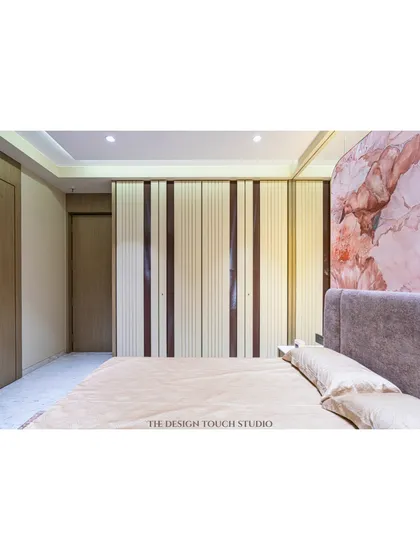 This bedroom features a beautiful floral marble-patterned headboard that serves as a stunning focal point. The design combines this artistic element with sleek, modern wardrobes for a balanced look.